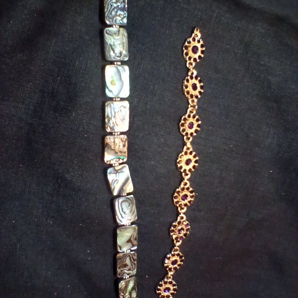 Two bracelets, one gold tone with purple stones, one with Onyx like shell.